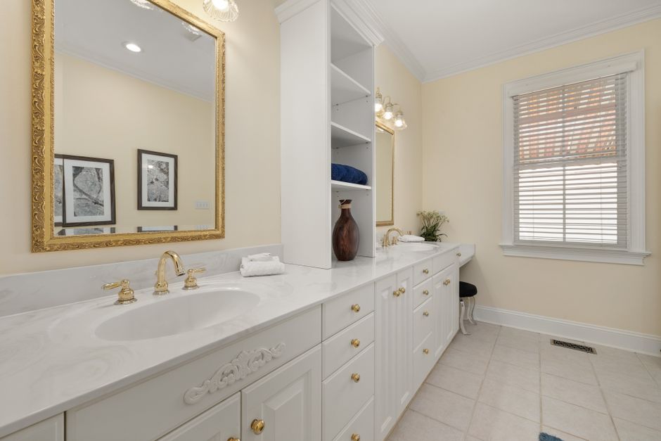Spacious bathroom with a double vanity, gold accents, and stylish decor creating a luxurious ambiance.