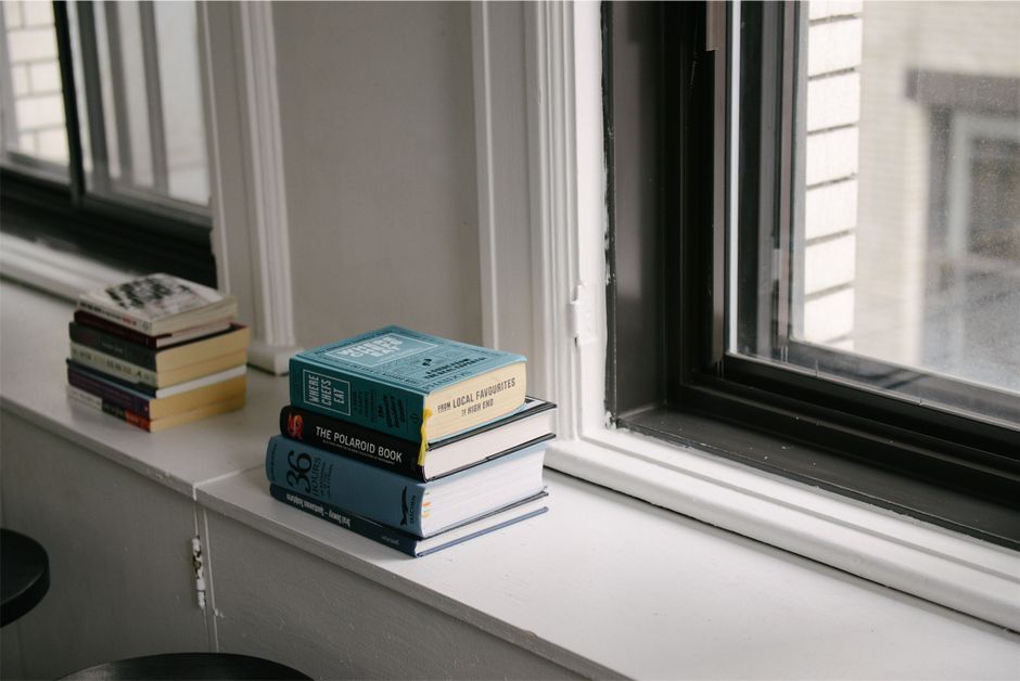 A peaceful indoor scene with books stacked on a windowsill, perfect for reading.