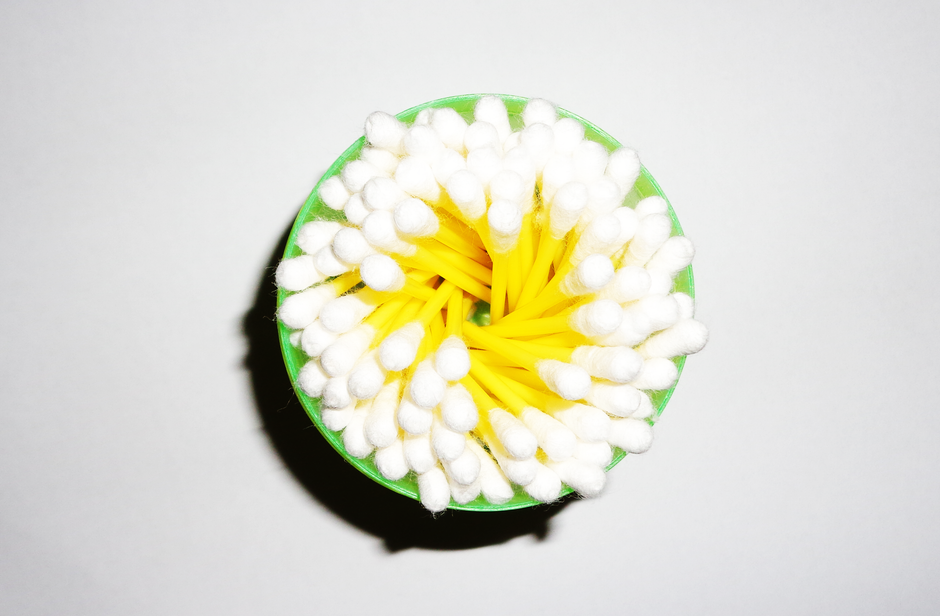 A close-up image of cotton swabs arranged inside a green plastic cup, viewed from above.